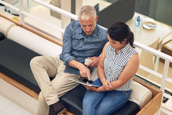 A consultant and a student reviewing a college list together on a tablet.